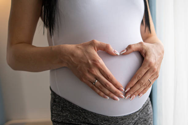 Pregnant woman belly with heart Pregnant woman. Closeup to her abdomen. surrogacy stock pictures, royalty-free photos & images