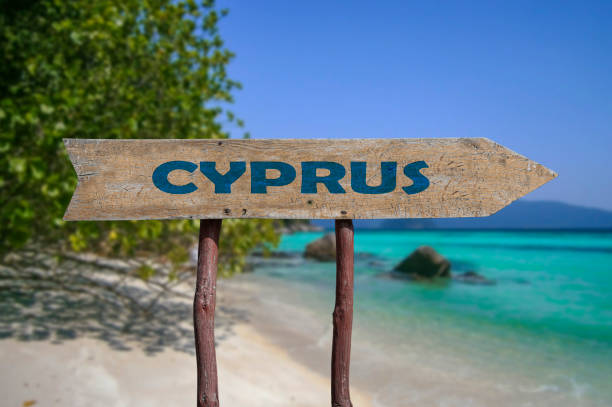 Cyprus wooden arrow road sign against beach with white sand and turquoise water background. Travel to Cyprus concept. stock photo
