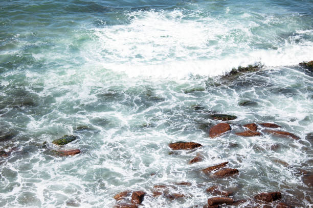 istock Blue waters with waves natural background. White ocean foam. Waves beating against dark rocks. 1308892953