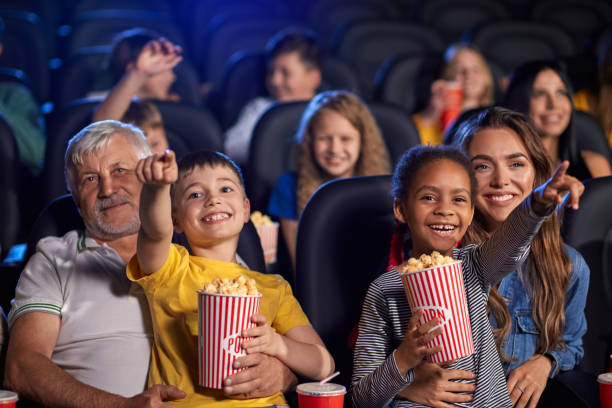 Parents with kids on knees in cinema. stock photo