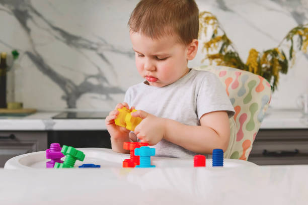 istock Child boy 2 y.o. plays with plastic colored shaped large screws and nuts, learning through the game. 1308896169