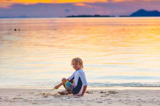 istock Child playing on ocean beach. Kid at sunset sea. 1308897494