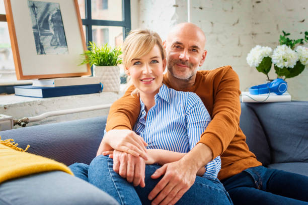 istock Happy couple sitting on couch while relaxing at home 1308898181