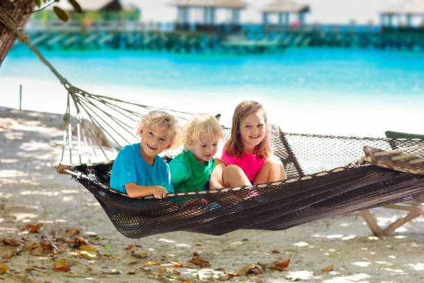 Kids relax in hammock. Children playing at tropical beach on family summer vacation on exotic island. Travel with little child. Relaxing holiday at sea side with young kid. Luxury resort in Asia.