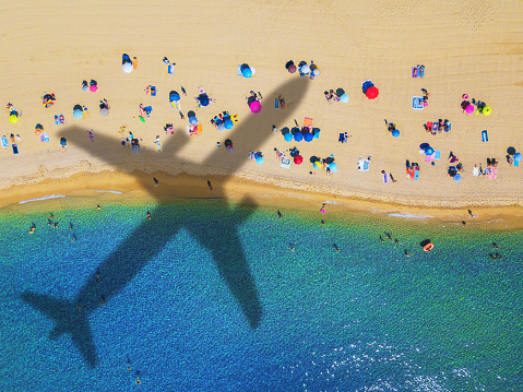 Waves on the beach with shadow of commercial airplane flying above beautiful tropical beach