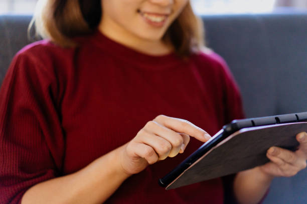 istock Smiling young asian woman using digital tablet at home 1308901833