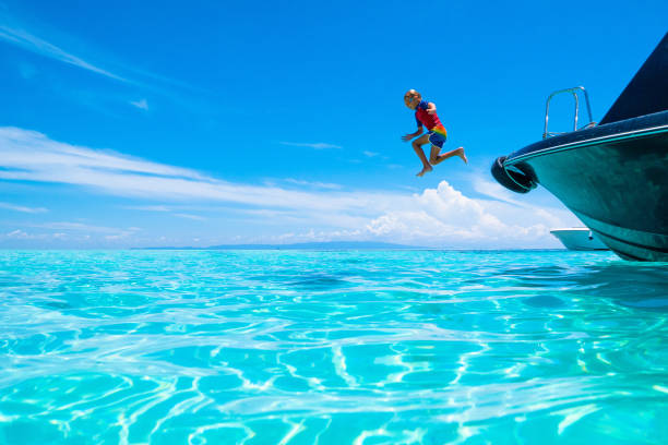 niño saltando al agua del mar. vacaciones en yates. - clear sky water sports and fitness yacht fotografías e imágenes de stock