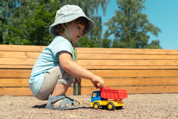 屋外でおもちゃの車で座って遊んでいる小さな男の子の肖像画 - playground cute baby blue ストックフォトと画像