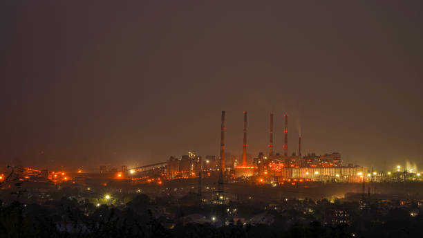 Night urban landscape with an industrial complex Night urban landscape with an industrial complex with its metal structures and chimneys with reflection of lamps with yellow lights of the city. kolkata night stock pictures, royalty-free photos & images