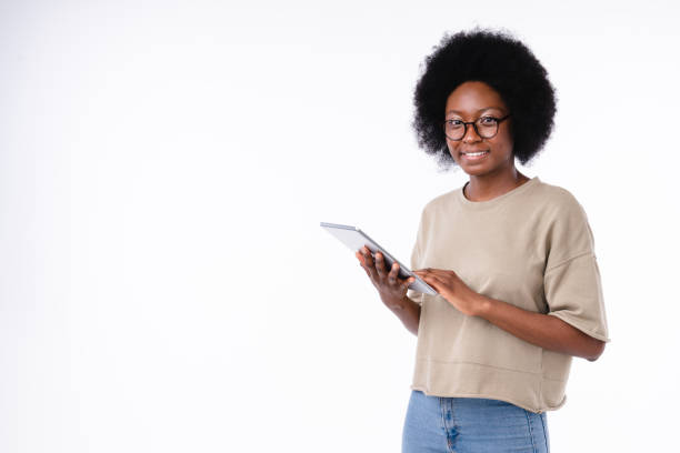 confiante menina afro-americana confiante usando tablet isolado sobre fundo branco - african ethnicity standing college student curly hair - fotografias e filmes do acervo