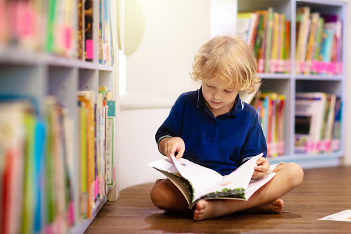 Child in school library. Kids read books. Little boy reading and studying. Children at book store. Smart intelligent preschool kid choosing books to borrow.