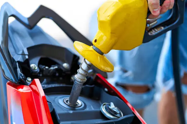 Photo of Refueling a motorbike. Close-up of a fuel nozzle inserted into a gas tank