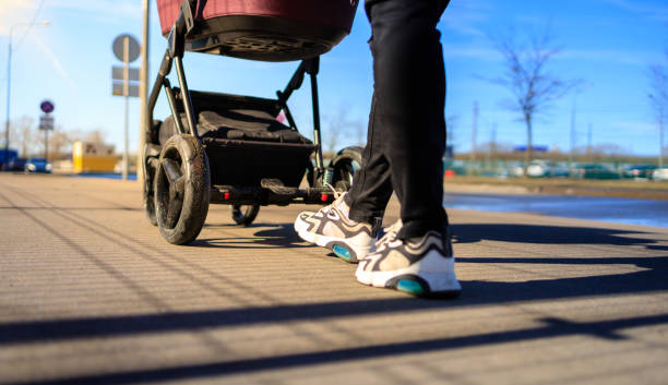 mom walks on the street with a baby in a stroller, stroller close-up, bottom view stock photo