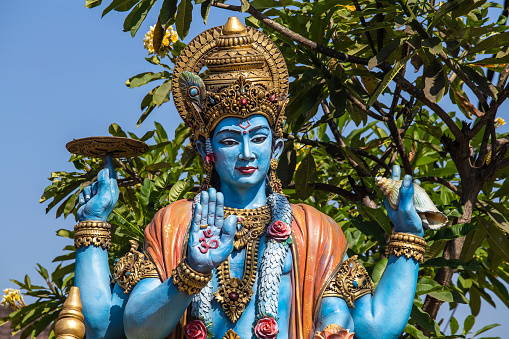 Detail stone statue in indian hindu temple on blue sky background, close up