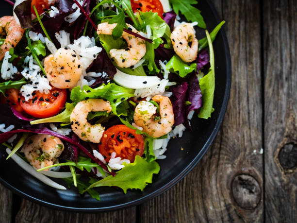 istock Prawn salad - prawns with white rice and vegetables on wooden table 1308925463