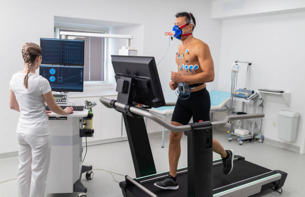 Male Athlete Performing ECG and VO2 test on Treadmill Young adult man having a VO2 test with a VO2 mask on his face, electrocardiogram pads attached, treadmill cardio pulmonary stock pictures, royalty-free photos & images