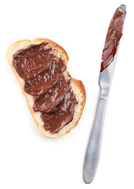 istock Piece of bread with chocolate paste and knife on white background, isolated. Top view 1308932862
