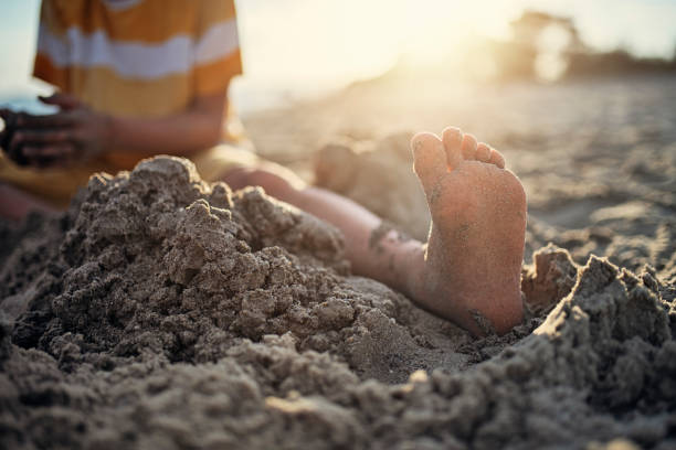 brüder mit spaß am strand, nahaufnahme des fußes - lifestyles child beach digging stock-fotos und bilder