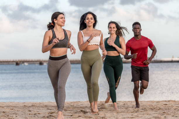 istock Happy diverse man and women running on beach 1308936005