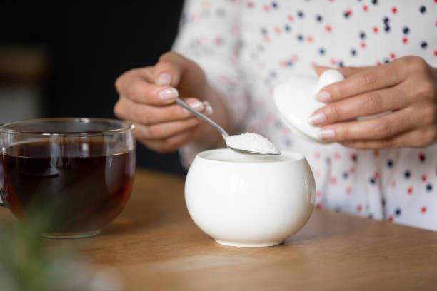 młoda dama parząca herbatę dodać łyżeczkę cukru do filiżanki - sugar flowers zdjęcia i obrazy z banku zdjęć