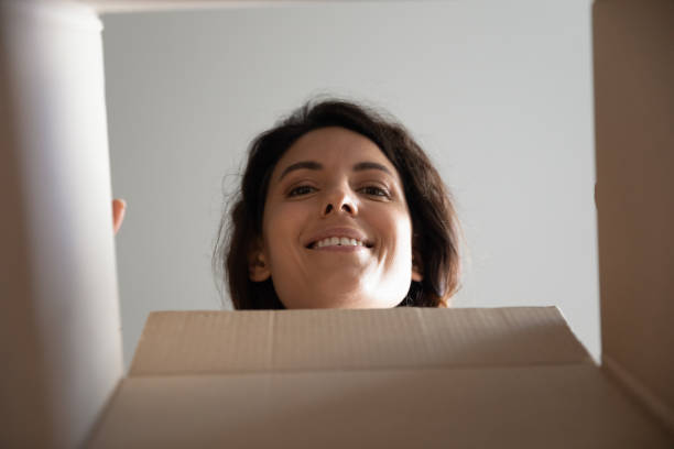 istock Curious millennial female face look inside cardboard box postal parcel 1308937346
