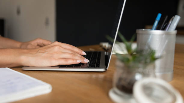 istock Young woman sitting by table at home office using laptop 1308937386
