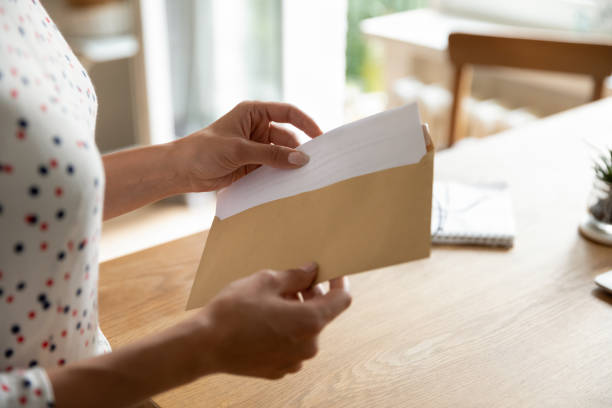 female hands put letter in envelop before send by mail - opening mail letter envelope imagens e fotografias de stock
