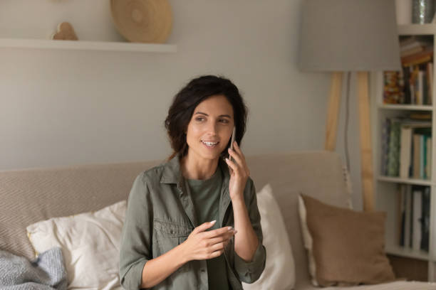 Tranquil millennial female enjoy phone conversation holding gadget at ear