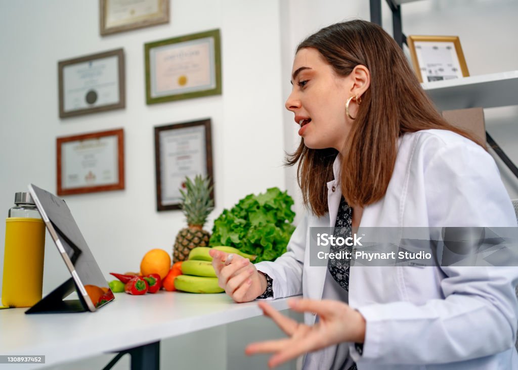 Nutritionist uses a digital tablet to conduct an online consultation with her patient Nutritionist Stock Photo