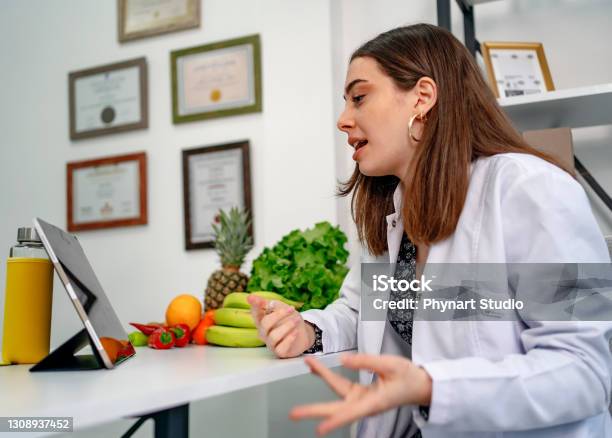 Nutritionist Uses A Digital Tablet To Conduct An Online Consultation With Her Patient Stock Photo - Download Image Now