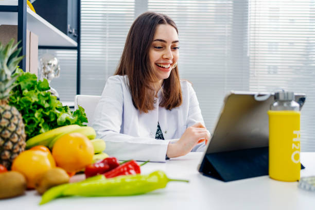 ernährungsberaterin verwendet ein digitales tablet, um eine online-konsultation mit ihrer patientin durchzuführen - ernährungsberater stock-fotos und bilder