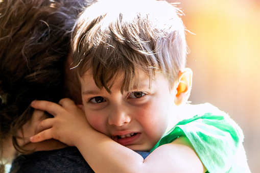 Caucasian Crying little boy embracing his mother looking at the camera