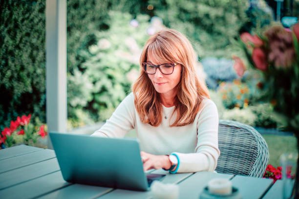 istock Confident woman using her laptop while sitting at balcony and working from home 1308942633