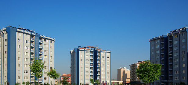 Group of residential apartment buildings in a row over sunny blue sky.