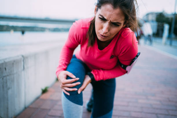 Sport Injury Young sporty woman feeling pain in her knee. Sportswoman holding her injured leg after jogging in the city. woman in pain stock pictures, royalty-free photos & images