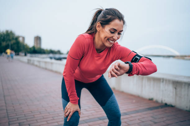 ジョギング後の時間をチェックするスポーティな若い女性。 - sport running exercising jogging ストックフォトと画像