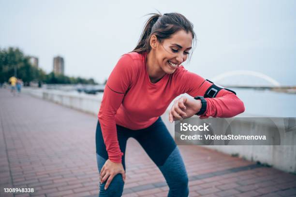 Sporty Young Woman Checking The Time After Jogging Stock Photo - Download Image Now