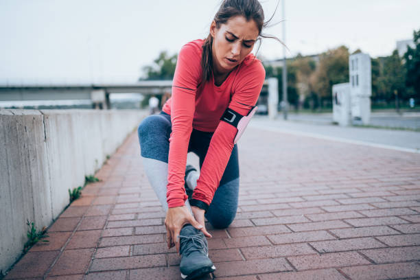 Sport Injury Young sporty woman feeling pain in her ankle. Sportswoman holding her injured leg after jogging in the city. sprain stock pictures, royalty-free photos & images