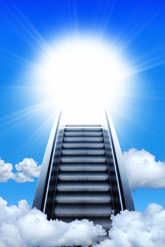 Conceptual success image of escalator stair way up to cloudy sky and shining beam of light