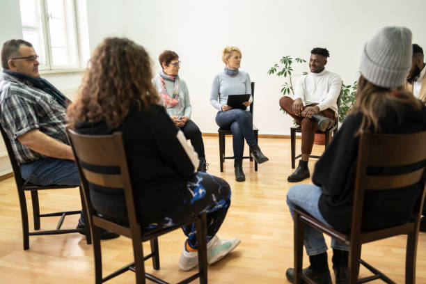 Group therapy support meeting talking about their mental health Group therapy support meeting talking about their mental health in a modern mental health facility career counseling stock pictures, royalty-free photos & images