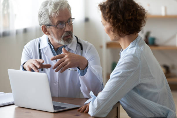 istock Senior doctor and patient discuss illness using laptop 1308951102