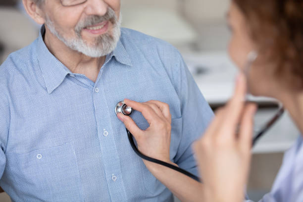 el primer plano de la enfermera femenina revisa los latidos maduros de los pacientes - chest stethoscope medical exam men fotografías e imágenes de stock