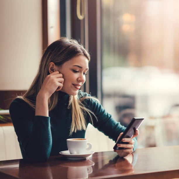 istock Young happy woman at restaurant drinking coffee and using mobile phone. 1308952134