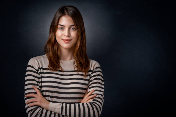 istock Attractive young woman studio portrait while standing at isolated dark background 1308952230