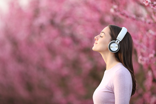 Woman relaxing listening to music with headphones in a pink field