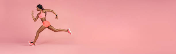 istock Sportswoman sprinting on a large pink background 1308958317