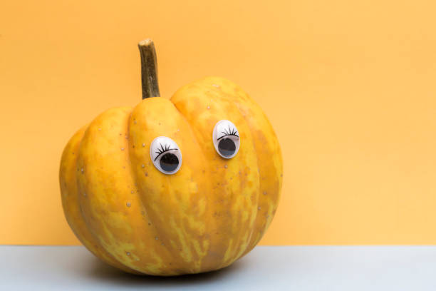 istock Funny overripe pumpkin with eyes on the orange background 1308959244