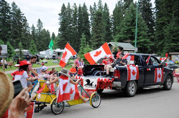bunte parade schwebt und menschen nehmen an einer parade teil, um den canada day im prince albert national park zu feiern. - prince albert national park stock-fotos und bilder