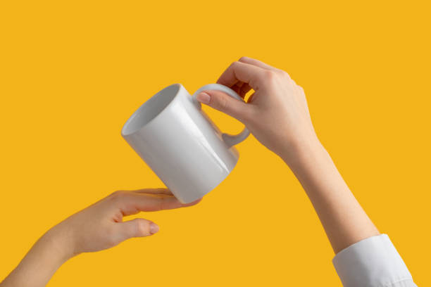 istock mockup ceramic white coffe cup or mug in female hands on yellow background with copy space. Blank template for your design, branding, business. Real photo. Woman in shirt casual style 1308961441