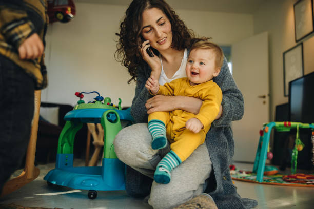 istock Mother holding baby while talking on phone 1308962342